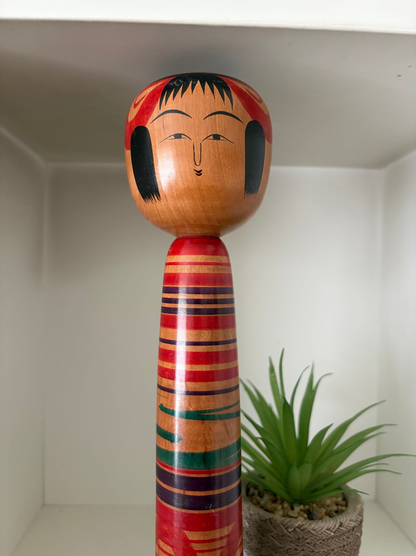 Vintage traditional Tsuchiyu kokeshi with striped design.